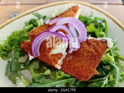 Fried saganaki cheese served on a plate with green salad Stock Photo