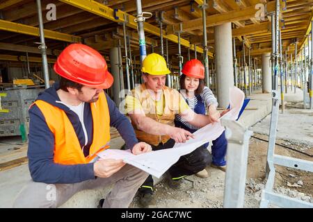 Craftsman team and architect discuss building drawings together on the building site in the shell Stock Photo