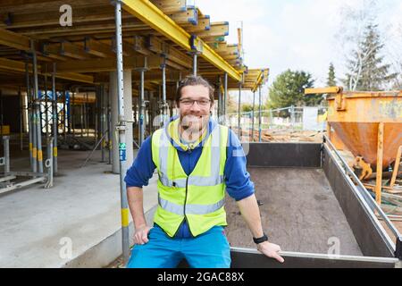 Smiling construction worker or craftsman apprentice on the shell of a construction site for house building Stock Photo