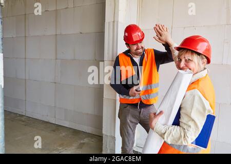 Happy architect welcomes foremen on the construction site with high five as motivation Stock Photo
