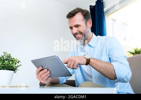 Handsome businessman working from home. Using app on tablet to telecommuting or sales reporting Stock Photo