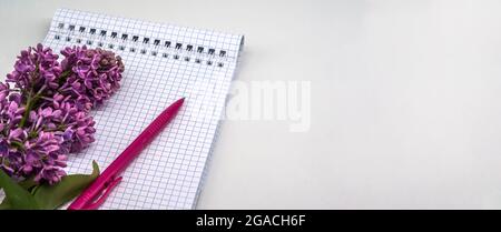 Notebook lilacs on white background. Spiral notebook and pen. Notepad with pen and flowers. Stock Photo