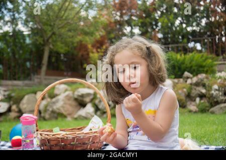 Little girl having a picnic in their garden on a hot summer day Stock Photo