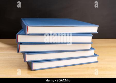 Pile of books on wooden table and black chalkboard at background. Back to school, education or learning concept Stock Photo