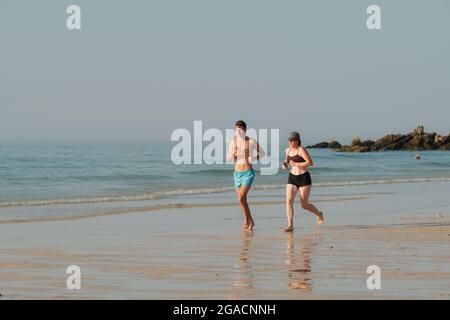 Young couple jogging along Porthmeor Beach at St Ives in Cornwall. Stock Photo