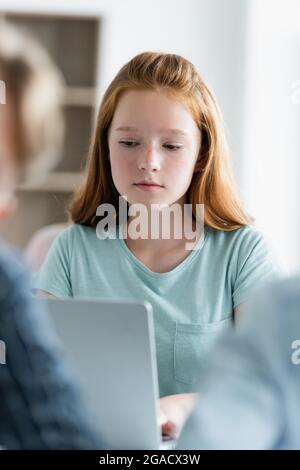 Teen schoolgirl using blurred laptop in classroom Stock Photo