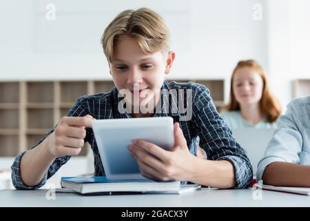 Smiling schoolboy using digital tablet near notebook Stock Photo