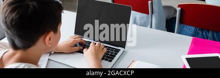 High angle view of boy using laptop in classroom, banner Stock Photo