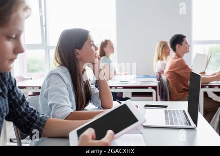 blurred boy using digital tablet near classmates during lesson Stock Photo