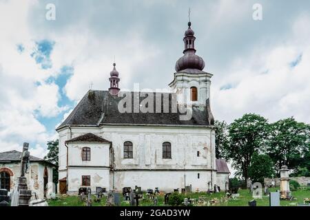 Puste Zibridovice,Czech Republic - July 12,2021. White old baroque Church of Saint Mary Magdalene with bell tower and cemetery in small Czech village Stock Photo