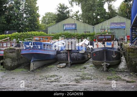 Houseboats sit on river mud at low tide at Johns Boatworks on Lots Ait - an island in the River Thames at Brentford, west London, UK Stock Photo