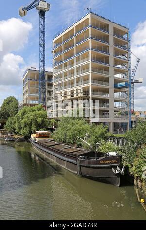 Construction of new apartment blocks next to the River Brent, London, UK. Part of a major residential development in Brentford. Shows tradional barge. Stock Photo