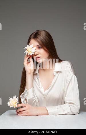 Young woman covering eye with fresh flower Stock Photo