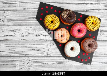 Several fresh donuts in a black ceramic plate on a wooden table with copy space Stock Photo