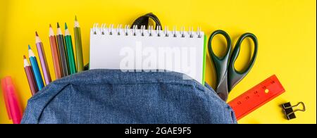 Flat lay student backpack and office supplies on a yellow background. Back to school concept. Banner format Stock Photo