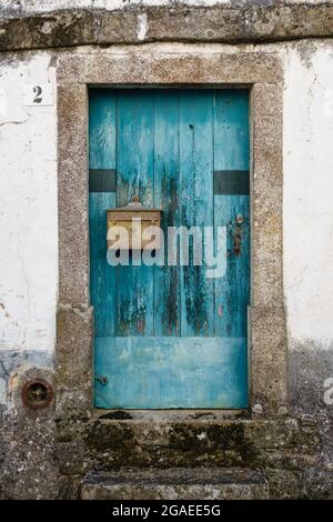 An old blue painted door in the wall of a cottage in the small town of Pedrógão Grande in central Portugal Stock Photo