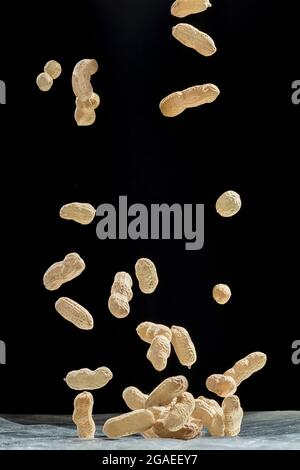 Realistic freeze motion of flying peanuts on black background. Stock Photo