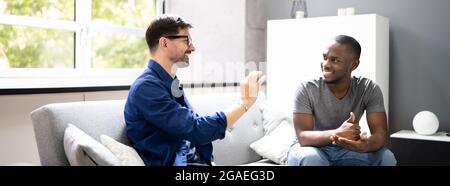Couple Using Sign Language. Deaf African American On Sofa Stock Photo
