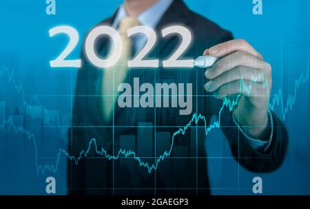 Businessman in suit forecast analysis plan profit chart. economic forecasts for 2022. businessman writes 2022 on virtual screen. economic recovery aft Stock Photo