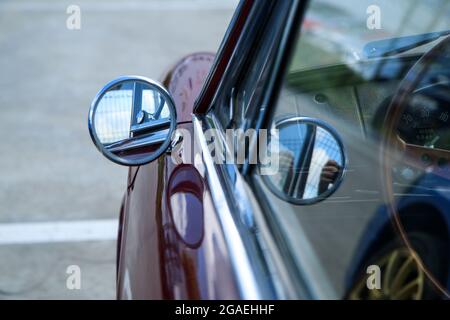 The detail of the simple small round side mirror on the classic Italian car. Chrome and shiny. Stock Photo