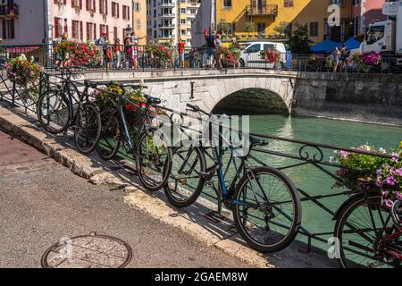 Bicycles parked near the Pont du Perriere in Annecy. Tourists stroll on the bridge visiting the city. Savoie department, France Stock Photo