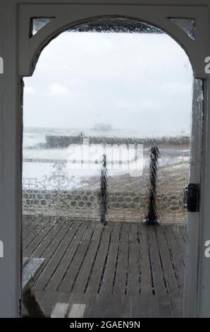 Brighton UK. 30 July 2021. Storm Evert seen through a window on Brighton's Palace Pier. 50mph winds battered the south of England today. Large waves crashed onto the beach at Brighton. © Stuart Walden/ Alamy