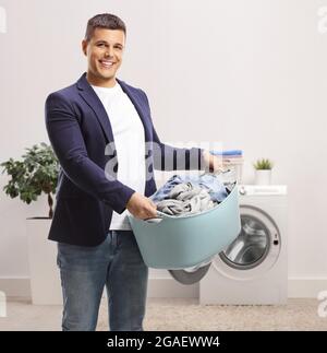 Smiling young man holding a laundry basket in a bathroom at home Stock Photo