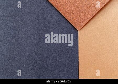 The background of the sandpaper surface, where the grains of sand on the sandpaper can be seen, and the difference in colors on the sandpaper indicate Stock Photo