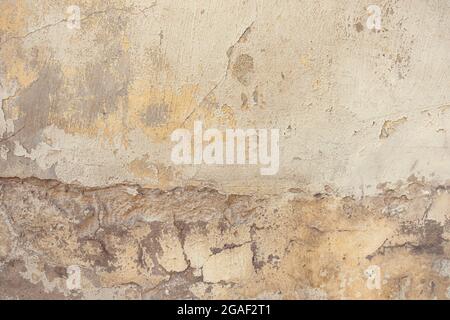 Old cracked weathered painted wall background texture. Dirty peeled plaster wall with falling off flakes of paint Stock Photo
