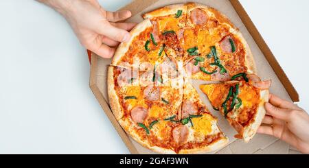 People taking slices of tasty pepperoni pizza at light background, top view with copy space. Pizza banner or italian food banner Stock Photo