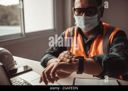 An engineer checks the time by looking at a smartwatch. Stock Photo