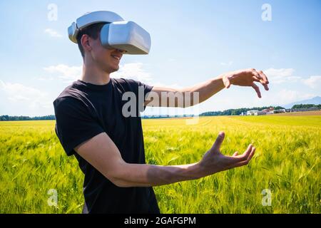 Man using virtual reality glasses outside in nature on a wheat farming field. Stock Photo