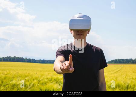 Man using virtual reality glasses outside in nature on a wheat farming field. Stock Photo