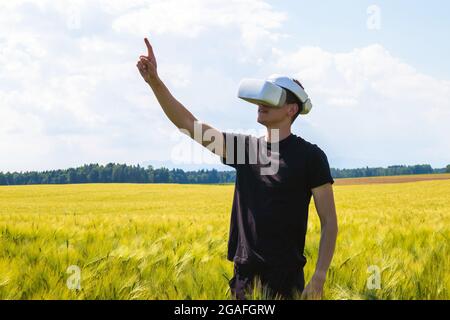 Man using virtual reality glasses outside in nature on a wheat farming field. Stock Photo