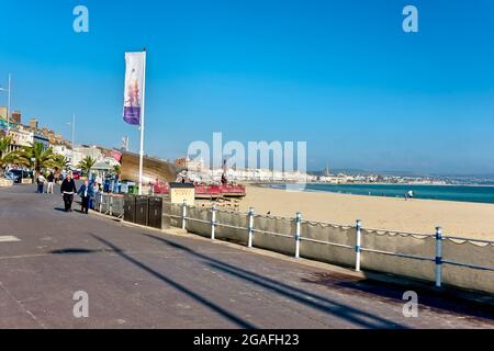 Weymouth, Dorset, UK - October 10 2018: People walking on an almost deserted Weymouth Promenade and beach in Dorset, England, UK