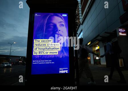 London, U.K. - 24 June 2021: An illuminated billboard encourages people to get vaccinated during the coronavirus pandemic. Stock Photo