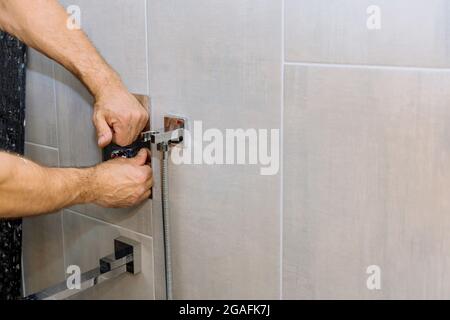 Installing a new on shower mixer tap in a bathroom Stock Photo
