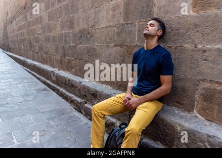Young latin man sitting thoughtful in the city Stock Photo