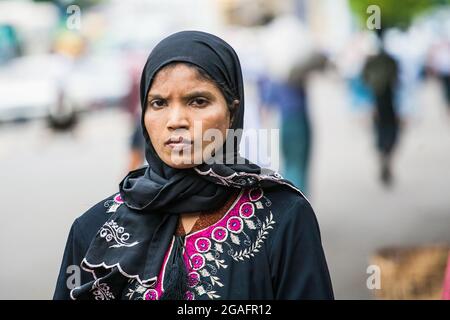 Burmese Muslim female wearing hijab stands staring frowning at camera, Yangon, Myanmar Stock Photo