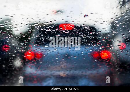 Bokeh, chuva, gotas de água pelo vidro do carro. Dia chuvoso. Lanternas de carros desfocadas. Colorido. Stock Photo