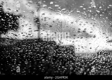 Bokeh, chuva, gotas de água pelo vidro do carro. Dia chuvoso. Lanternas de carros desfocadas. Colorido. Stock Photo