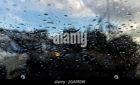 Bokeh, chuva, gotas de água pelo vidro do carro. Dia chuvoso. Lanternas de carros desfocadas. Colorido. Stock Photo