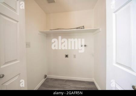 Empty laundry room interior with electrical socket and wall mounted faucet Stock Photo
