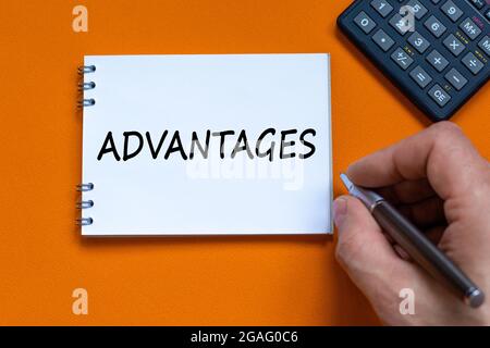Advantages symbol. Concept word 'advantages' on white note. Black calculator. Beautiful orange background. Business and advantages concept, copy space Stock Photo