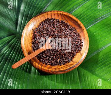 Raw brown mustard seeds in the wooden bowl Stock Photo