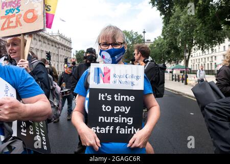 A protester holds a placard that says 'It's time to pay nursing staff fairly' during the demonstration.Members of the National Health Service (NHS) gathered outside St. Thomas' Hospital before marching towards Downing Street in a demonstration demanding fair pay for NHS workers, as the government's revised 3% pay rise was deemed hardly satisfactory. Issues addressed included long working hours, understaff and a lack of proper protection materials for the health workers. The demonstration was was led by NHS Workers Say No, supported by United the Union, GMB Union, and the Royal College of Nursi Stock Photo