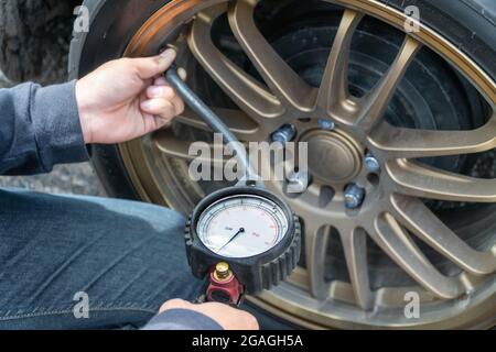 Tire Pressure Gauge and technician hands checking tyre pressure Stock Photo
