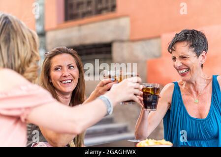 Adult woman with short hair in a cafe toasting with drinks with her friends Stock Photo