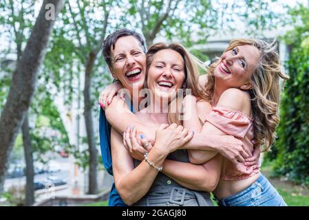 Close up of three cheerful mature female friends hugging together Stock Photo