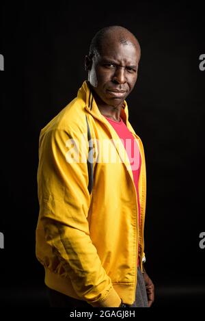Side view of a black man standing looking distrustful. black background Stock Photo